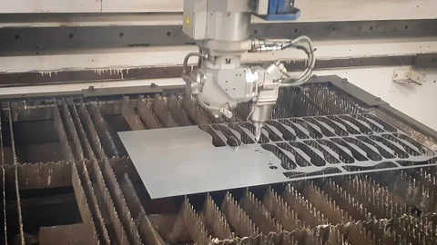 A computer numerical control (CNC) laser cutter cuts through stainless steel Stock Footage 105683359