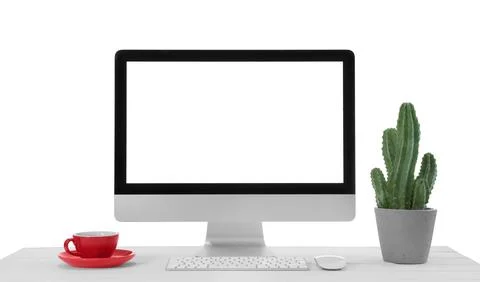 Computer, potted cactus and cup of drink on table against white background... Stock Photos