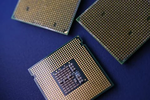 A computer processor on a blue background. Contacts on the processor case. Stock Photos