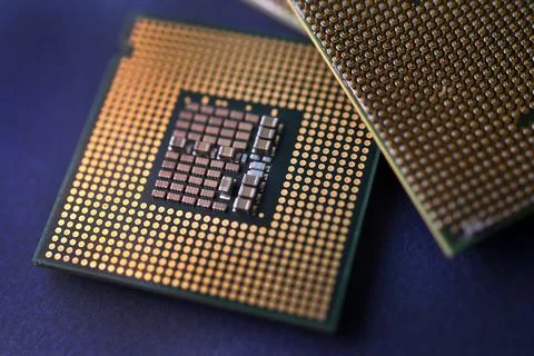 A computer processor on a blue background. Contacts on the processor case. Stock Photos