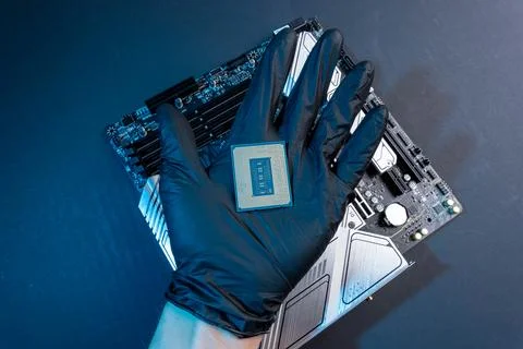 Computer processor in a gloved hand against the background of the motherboard Foto stock