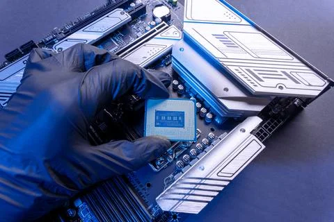 Computer processor in a gloved hand against the background of the motherboard Foto stock
