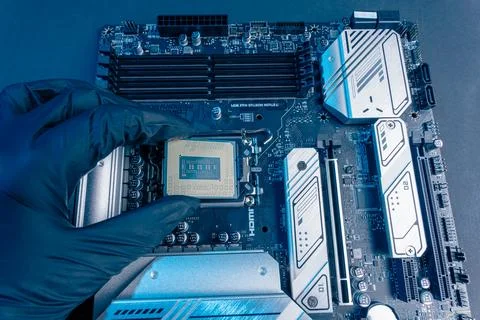 Computer processor in a gloved hand against the background of the motherboard Foto stock