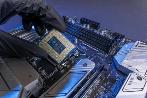 Computer processor in a gloved hand against the background of the motherboard Foto stock