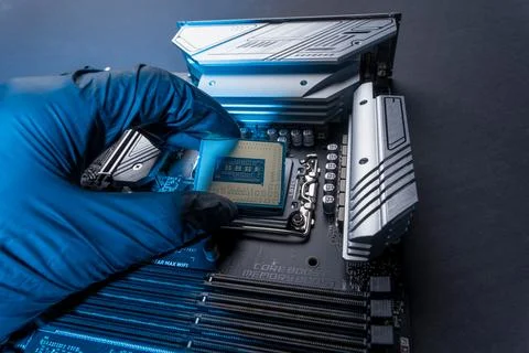 Computer processor in a gloved hand against the background of the motherboard 스톡 사진