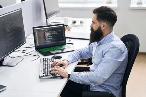 Computer programmer developer working in IT office, sitting at desk and coding Stock Photos