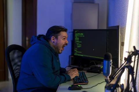 Computer programmer with an enthusiastic expression working in front of two moni Stock-Fotos