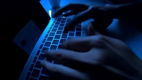 A computer programmer or hacker prints a code on a laptop keyboard to break i Stock Footage 117591736