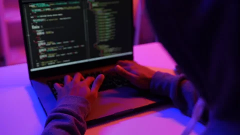 A computer programmer or hacker prints a code on a laptop keyboard to break into Video stock 325556482