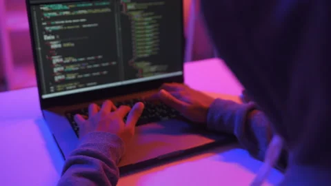 A computer programmer or hacker prints a code on a laptop keyboard to break into Stock Footage 327388223