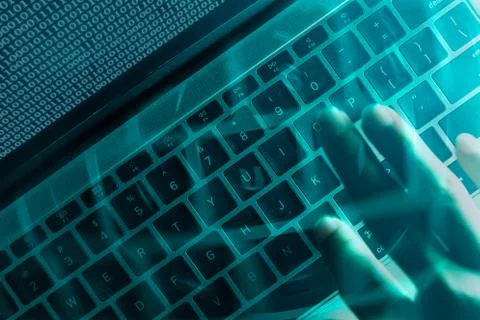 A computer programmer or hacker prints a code on a laptop keyboard to break i 스톡 사진