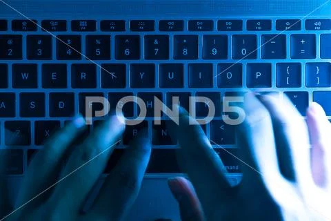 A computer programmer or hacker prints a code on a laptop keyboard to break i Stock Photos