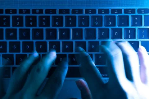 A computer programmer or hacker prints a code on a laptop keyboard to break i Foto stock
