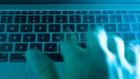 A computer programmer or hacker prints a code on a laptop keyboard to break i Stock Photos