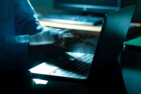 A computer programmer or hacker prints a code on a laptop keyboard to break i 스톡 사진