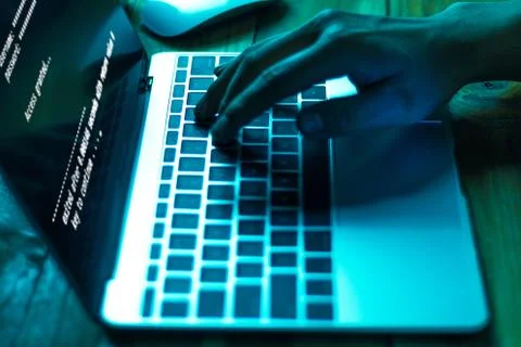 A computer programmer or hacker prints a code on a laptop keyboard to break i Stock Photos