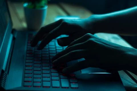 A computer programmer or hacker prints a code on a laptop keyboard to break i 스톡 사진