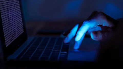 A computer programmer or hacker prints a code on a laptop keyboard to break i Stockfoto's