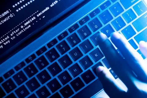 A computer programmer or hacker prints a code on a laptop keyboard to break i Foto stock