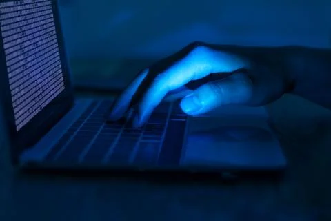 A computer programmer or hacker prints a code on a laptop keyboard to break i 스톡 사진