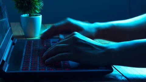 A computer programmer or hacker prints a code on a laptop keyboard to break i 写真素材