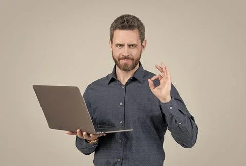 Computer programmer show ring gesture holding portable laptop grey background 写真素材