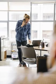 Computer programmer talking on smart phone in office 写真素材