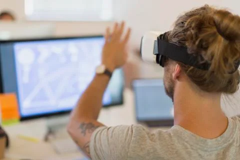 Computer programmer testing virtual reality simulator glasses at computer in Stock Photos
