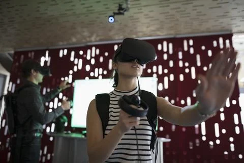 Computer programmer testing virtual reality simulator glasses and joysticks in o Stock Photos