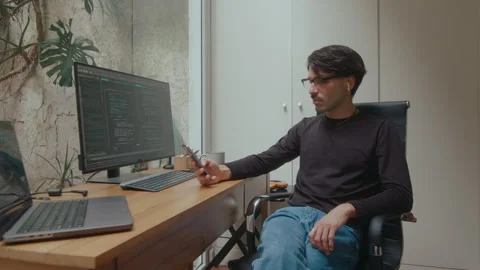 Computer Programmer Using Phone in Home Office Video stock 252758956