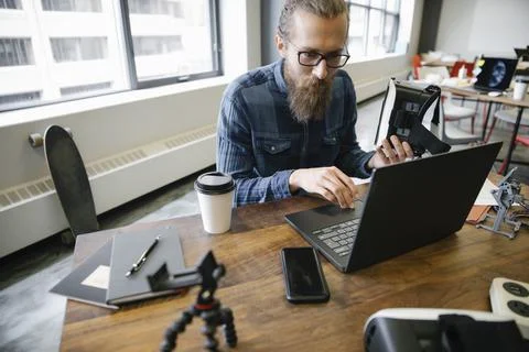 Computer programmer with virtual reality simulator glasses working at laptop in Stock Photos