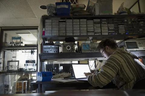 Computer programmer working at laptop in dark workshop 写真素材