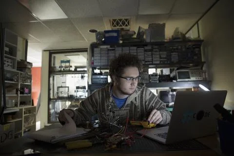 Computer programmer working at laptop in dark workshop Stock Photos
