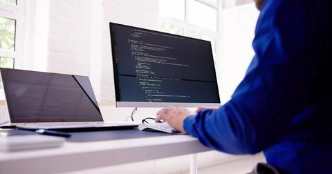 Computer Programmer Writing Program Code On Computer In Office Stock Photos