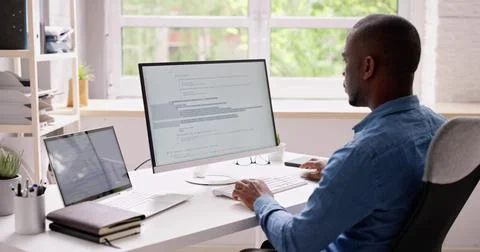 Computer Programmer Writing Program Code On Computer In Office Stock Photos
