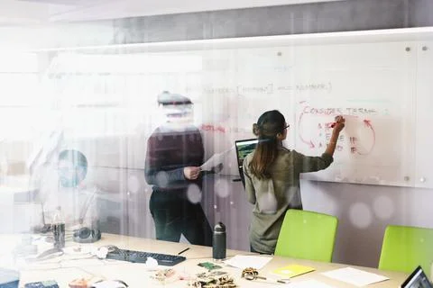 Computer programmers brainstorming at whiteboard in conference room meeting Stock-Fotos