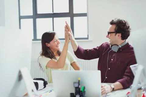 Computer programmers high-fiving at laptop in office Stock-Fotos