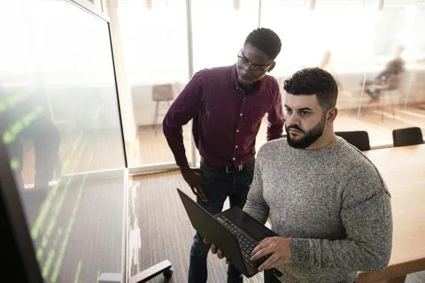 Computer programmers with laptop working at projection screen Stock Photos