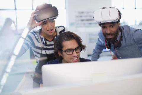 Computer programmers programming virtual reality simulators at computer in Foto stock