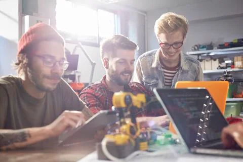 Computer programmers using laptops and digital tablet, programming robotics in Foto stock