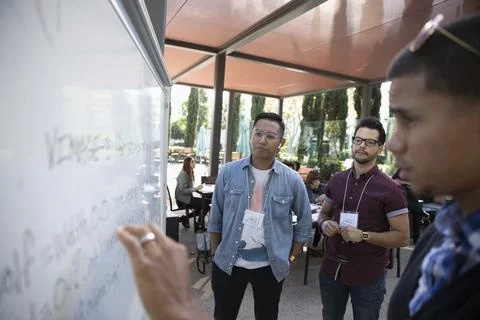 Computer programmers using touch screen whiteboard during meeting Stock Photos