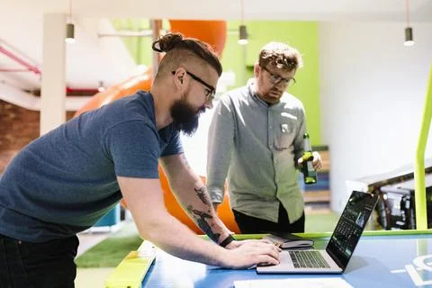 Computer programmers working at laptop and drinking beer in office Stock-Fotos