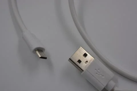 Computer quipment long, white micro USB cable for phone, computer located. Stock Photos