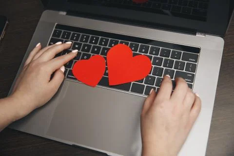 Computer with red hearts on table close up Stock Photos