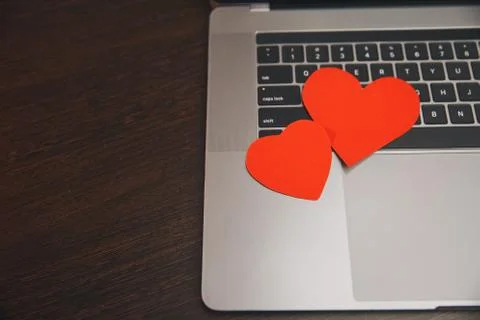 Computer with red hearts on table close up Stock Photos