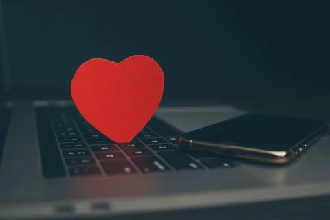 Computer with red hearts on table close up Stock Photos