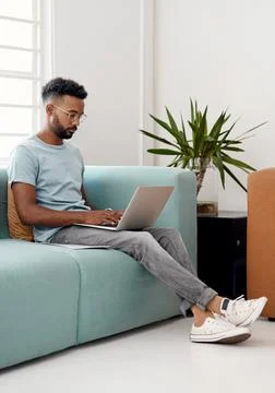 Computer, remote work and  man typing on sofa for research, project or Stock Photos