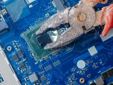 Computer repair concept. Old rusty passages on a blue laptop motherboard. The Stock Photos