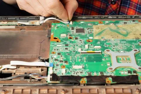 A computer repair technician disassembles a laptop for further cleaning or re Stock Photos