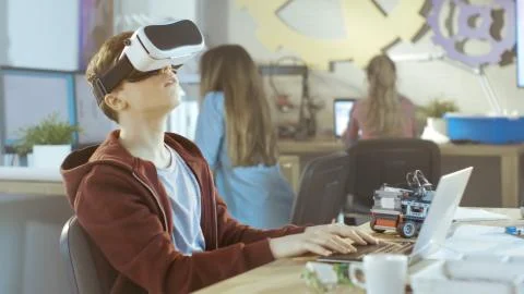 In a Computer Science Class Boy Wearing Virtual Reality Headset Works on a Pr Stock Photos